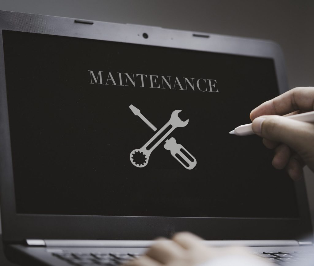 Businessman using computer laptop with maintenance sign on monitor screen for technical support customer service concept.